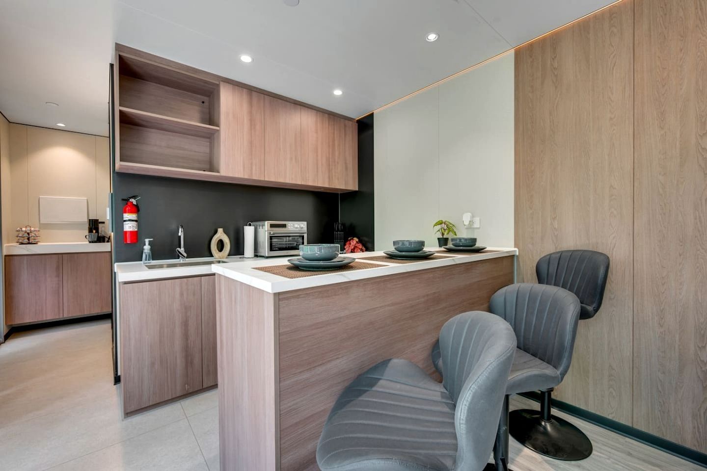 A modern kitchen with a central island, built-in cabinets, a microwave, and a coffee machine.