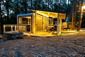 A modern, well-lit cabin with a deck, a TV, and a sign advertising a nearby attraction. - Stargazing Luxury Pod Retreat with Hot Tub in Broken Bow, Oklahoma (Broken Bow)