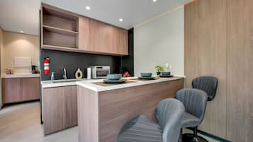 A modern kitchen with a central island, built-in cabinets, a microwave, and a coffee machine.