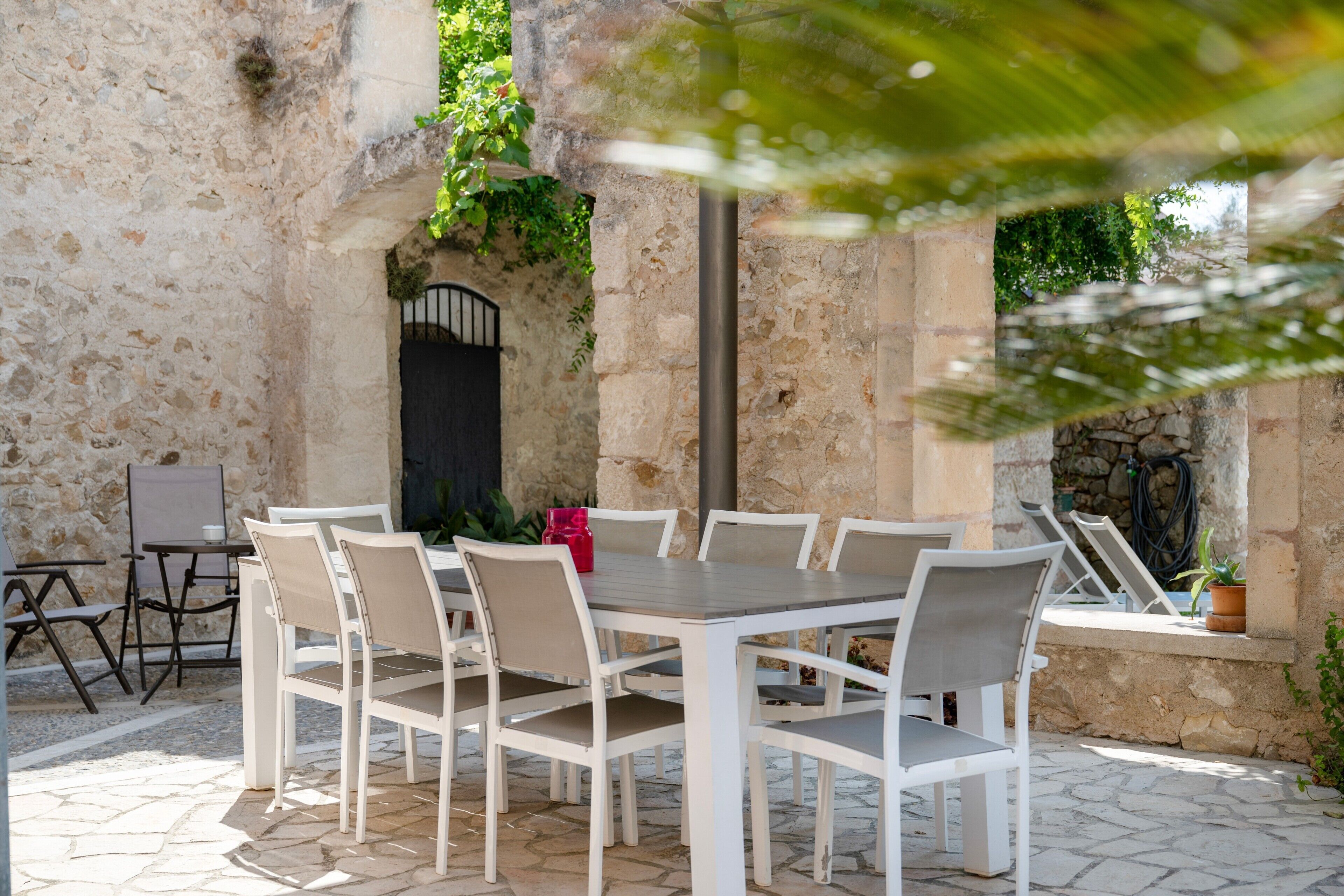 An outdoor patio with a stone wall, a table with chairs, and a door.