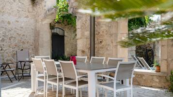 An outdoor patio with a stone wall, a table with chairs, and a door.