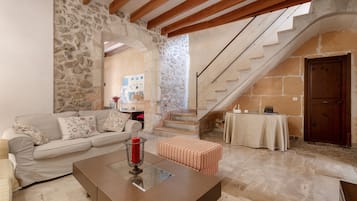 A living room with a stone wall, a staircase, a sofa, a coffee table, and a striped ottoman.