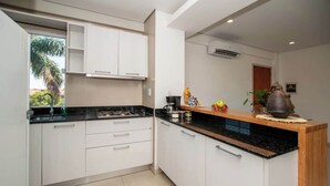 A kitchen with white cabinets, a black countertop, and a wooden island. - Corporate Stays Edificio Pilar - N2A1 (Asunción)