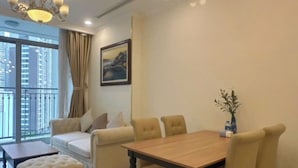 En moderne stue med spisebord, sofa, skammel og en lysekrone.