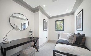 A bedroom with a bed, a desk, a chair, a mirror, and framed pictures on the wall. - Luxury 4BR Camden Villa w/ Parking & Garden (London)