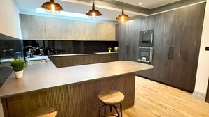 Una cucina moderna con isola centrale, sgabelli da bar e illuminazione a sospensione.
