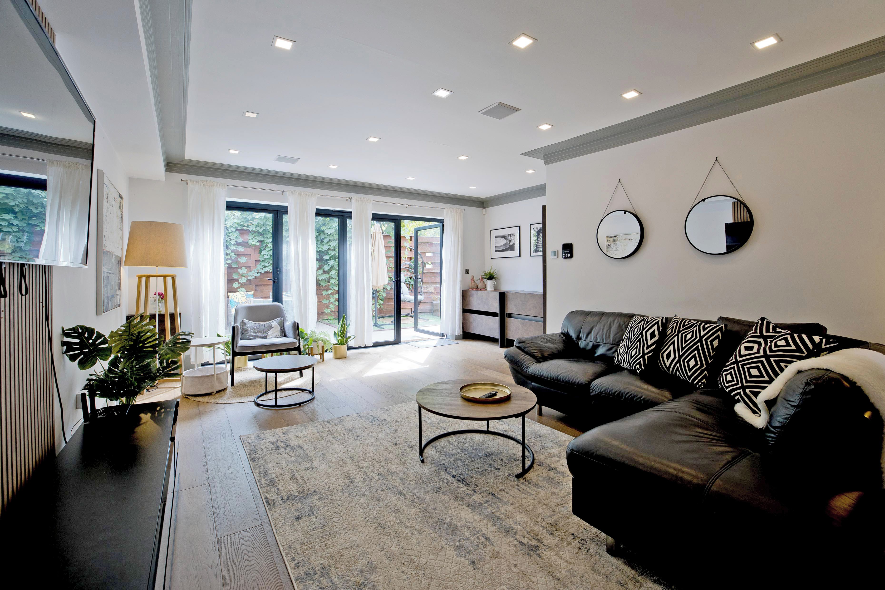 Un salon moderne avec un canapé en cuir, une table basse et une grande fenêtre agrémentée de rideaux.