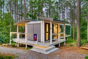 Eine moderne Hütte mit einer Terrasse, großen Fenstern und einem Schild mit der Aufschrift 'Lunar Lounge'.