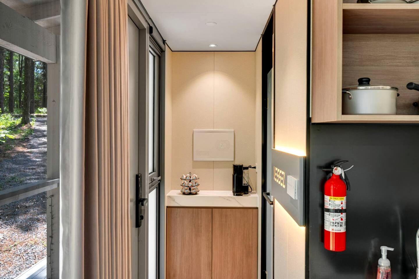 A modern kitchen with a built-in stove, a coffee maker, and a fire extinguisher on the wall.