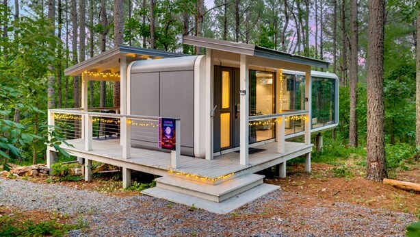Une cabane moderne dotée d’une terrasse, de grandes fenêtres et d’une enseigne indiquant « Lunar Lounge ».