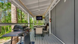 Une terrasse extérieure équipée d’un barbecue, de sièges et d’un écran de télévision.