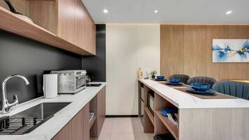 A compact kitchen with modern appliances, a dining area with a table set for two, and a minimalist decor.