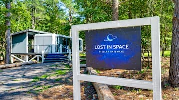 A sign with 'LOST IN SPACE' and 'STELLAR GATEWAYS' text, a cabin, and a forested area.