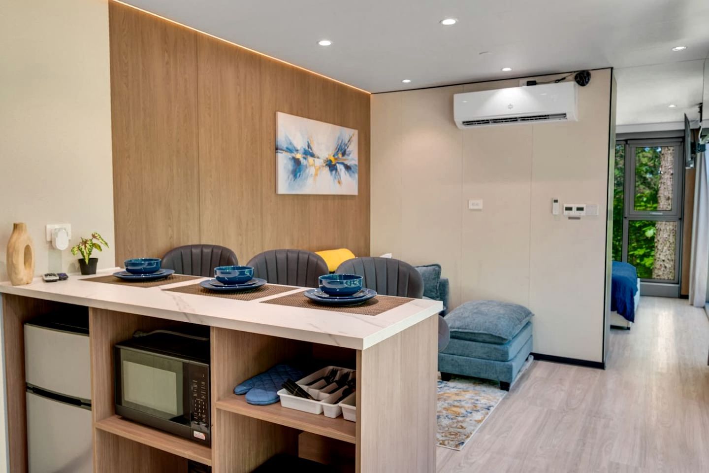 A modern kitchen with a dining area, a microwave, a coffee maker, and a blue sofa.
