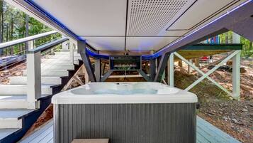A hot tub on a wooden deck with a view of a forested area.