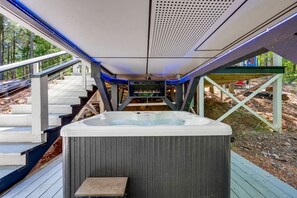 Ein Whirlpool auf einer Holzterrasse mit Blick auf ein bewaldetes Gebiet.