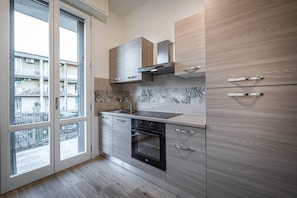 A modern kitchen with a large window, built-in oven, and wooden cabinetry. - Pietrafitta (Florence)