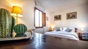 A hotel room with a bed, nightstands, a lamp, and a cactus on a tray. - Vellutini (Florence)