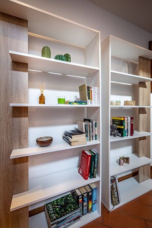 Ein modernes Bücherregal mit mehreren Ablagen, auf denen Bücher und dekorative Gegenstände stehen.