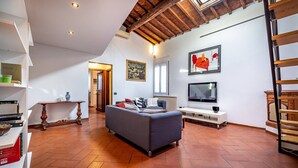 A living room with a sofa, TV, and artwork on the wall. - Vellutini (Florence)