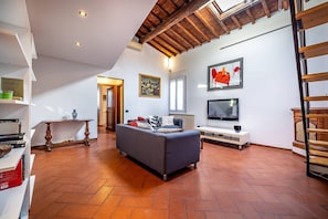 Ein Wohnzimmer mit einer Couch, einem Fernseher und Kunstwerken an der Wand.