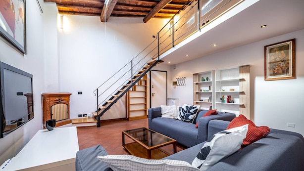 A modern living room with a sofa, coffee table, and a staircase leading to an upper level. - Vellutini (Florence)