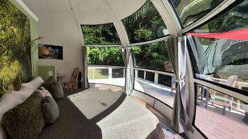 Un dormitorio con una cama grande, vistas al exterior, una mesita y una silla.