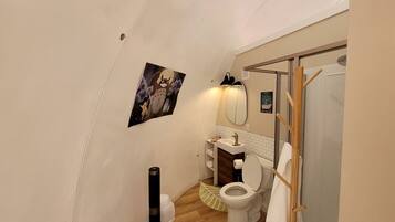 A compact bathroom with a toilet, sink, and shower.