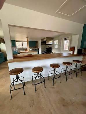 Een keuken met een houten kookeiland en barstoelen.