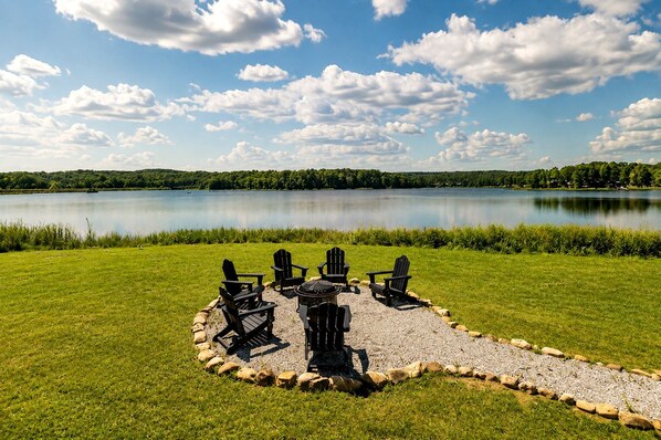 Un espace extérieur aménagé au bord du lac, avec des chaises Adirondack et un foyer.