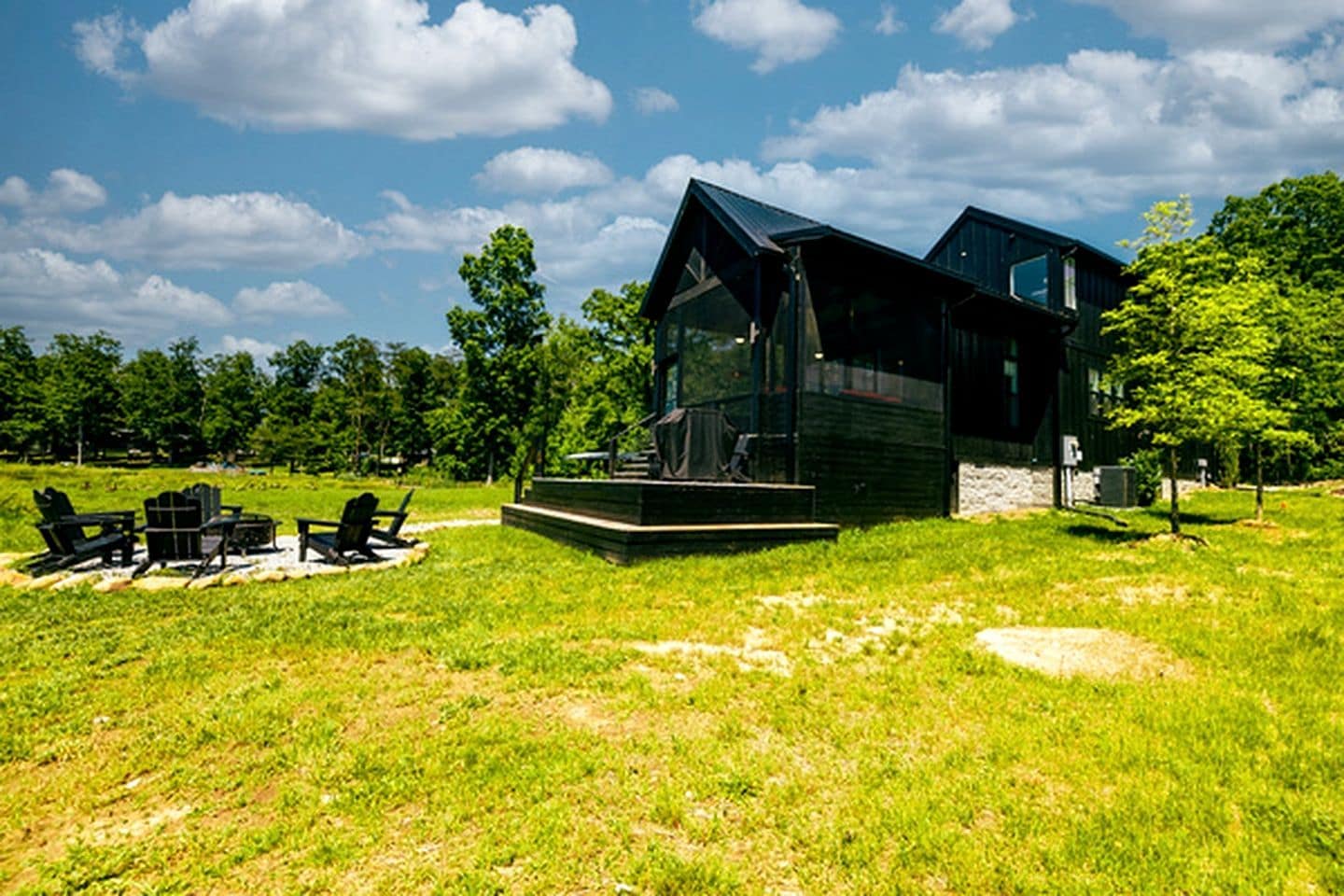 A modern house with a glass facade, a wooden deck, and outdoor furniture.
