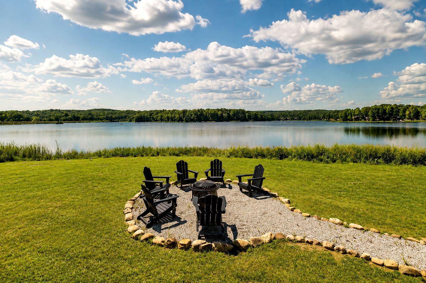 Un espace extérieur aménagé au bord du lac, avec des chaises Adirondack et un foyer.