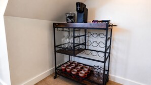 Ein winkelförmiger Regaleinbau mit mehreren Ablageflächen, auf denen Gläser und Tassen stehen, und eine Kaffeemaschine obenauf.