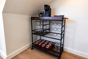 Ein winkelförmiger Regaleinbau mit mehreren Ablageflächen, auf denen Gläser und Tassen stehen, und eine Kaffeemaschine obenauf.