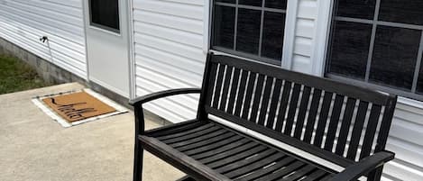 A bench outside a building with a window and a door.
