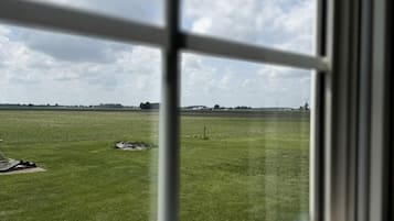 Uitzicht vanuit een raam op een grasveld met een heldere lucht.