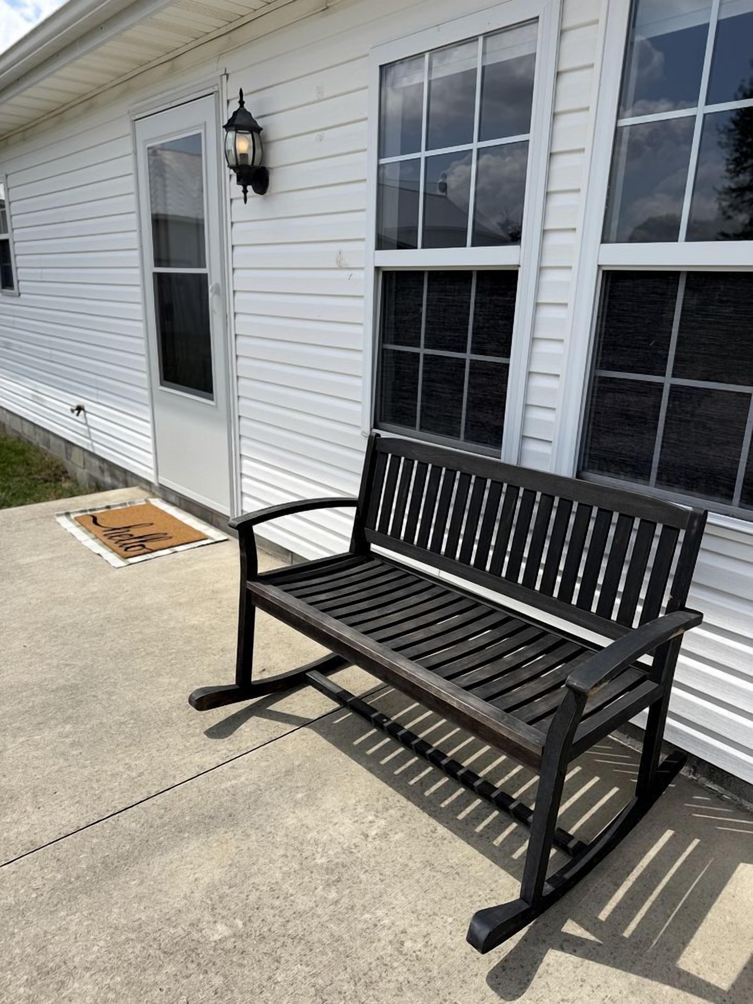 A bench outside a building with a window and a door.