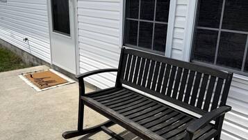 A bench outside a building with a window and a door.