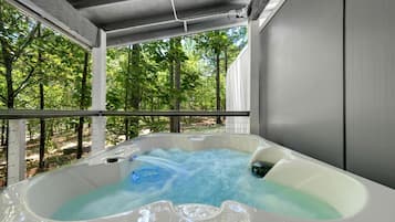 A hot tub with a view of a forested area.