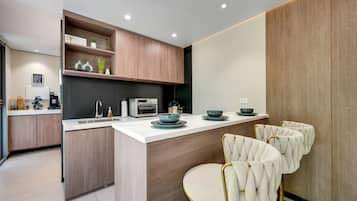 A modern kitchen with a central island, built-in appliances, and a seating area with tufted chairs.