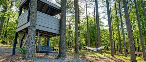 Una casa del árbol con un banco y una hamaca en un bosque.