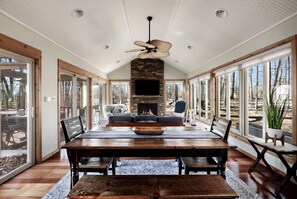 Um quarto espaçoso com uma grande mesa de jantar, assentos confortáveis, lareira e janelas amplas com vista para o exterior.
