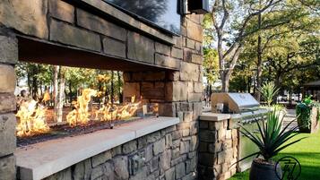 An outdoor barbecue area with a stone wall, a fire feature, and a grill.