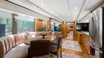 A modern interior with a dining area, seating, kitchen, and a large TV.