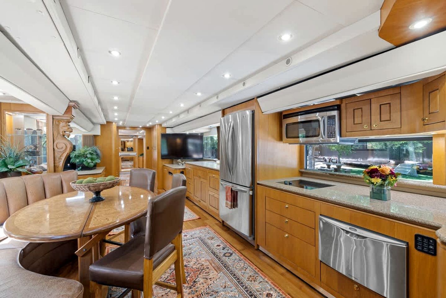 Et moderne køkken med rustfrie hvidevarer, træskabe og et spiseområde med et rundt bord og stole.