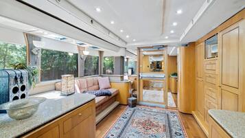 A compact, modern interior with a kitchenette, seating area, and large windows.