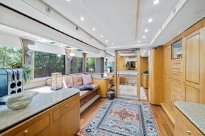 A compact, modern interior with a kitchenette, seating area, and large windows.
