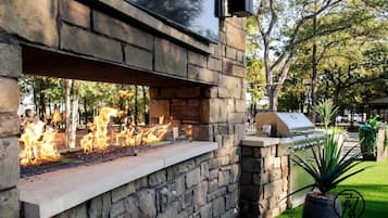 An outdoor stone wall with a built-in fire feature and a grill.