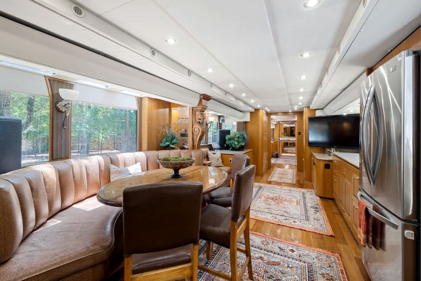 Een modern interieur met een eethoek, zitplaatsen, keuken en een grote televisie.