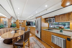 Una cocina moderna con electrodomésticos de acero inoxidable, armarios de madera y una zona de comedor con sillas de cuero.